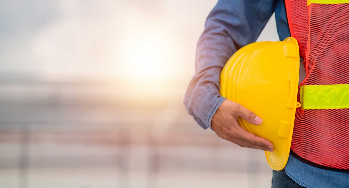 Un homme tient son casque de chantier contre lui