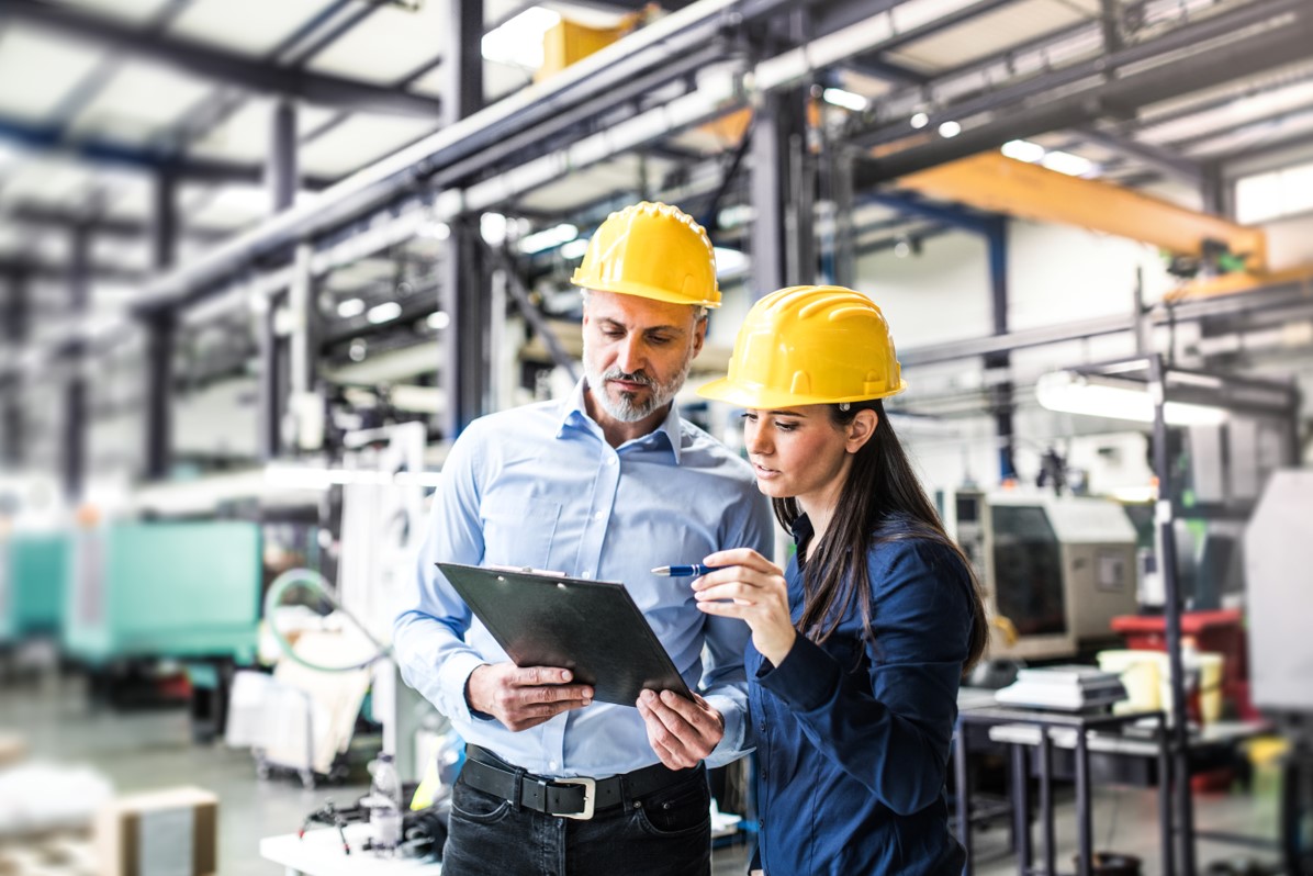 Un homme et une femme avec un casque jaune sont dans une usine