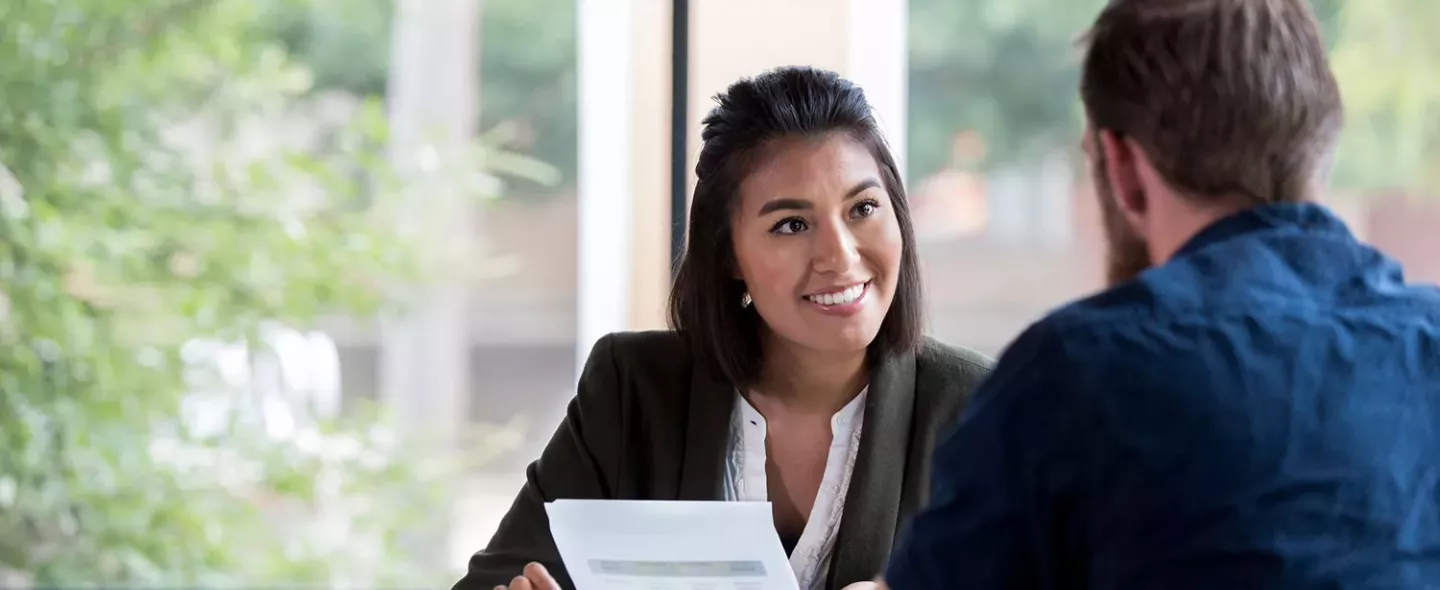 Une femme et un homme discutent à un bureau